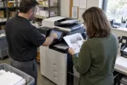 Copier technician demonstrating scanning and finishing to a facilities manager