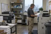 Facilities manager reviewing copier output and supplies in an office copy room